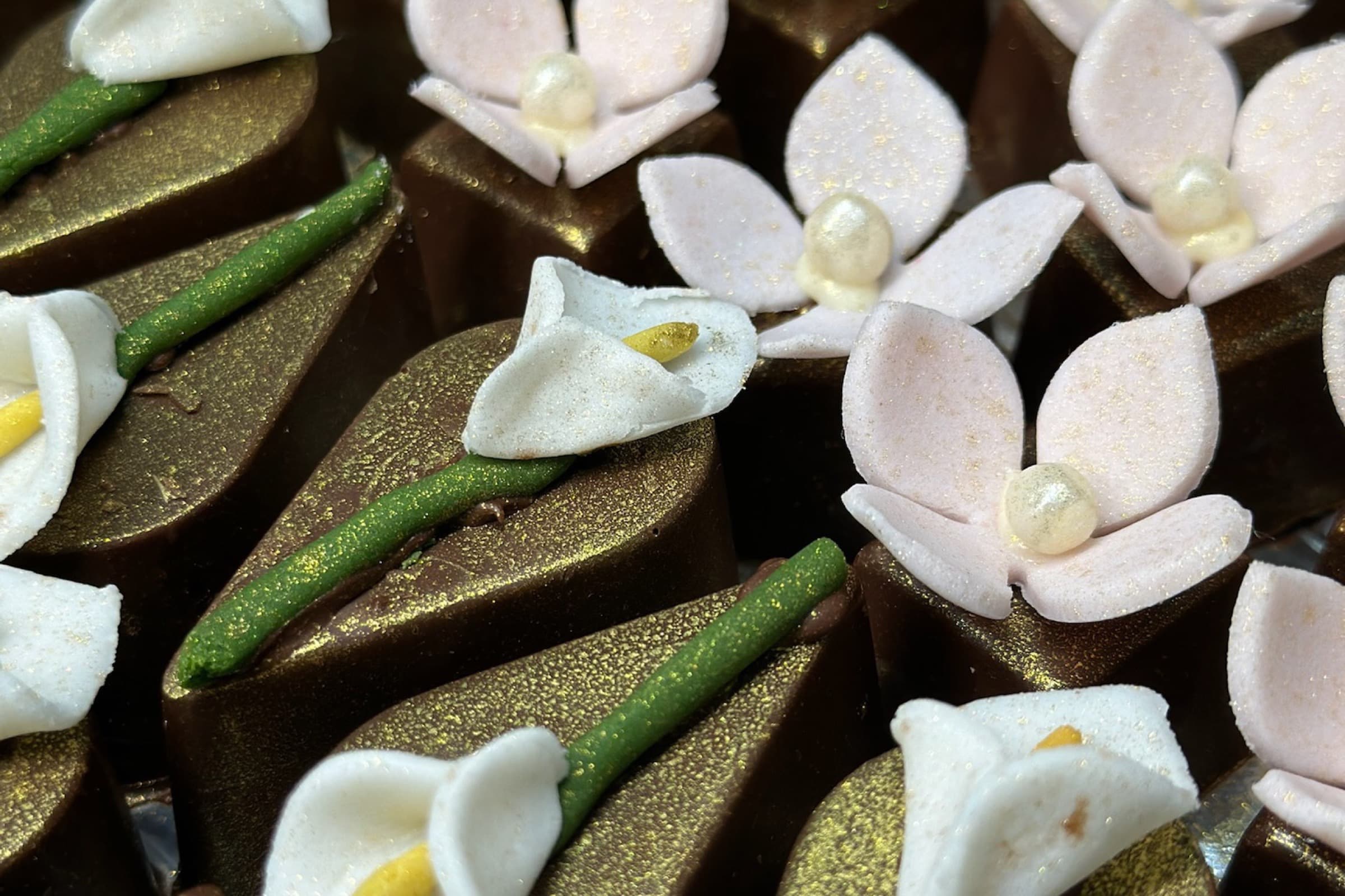 Chocolates florais artesanais com flores brancas e acabamento dourado