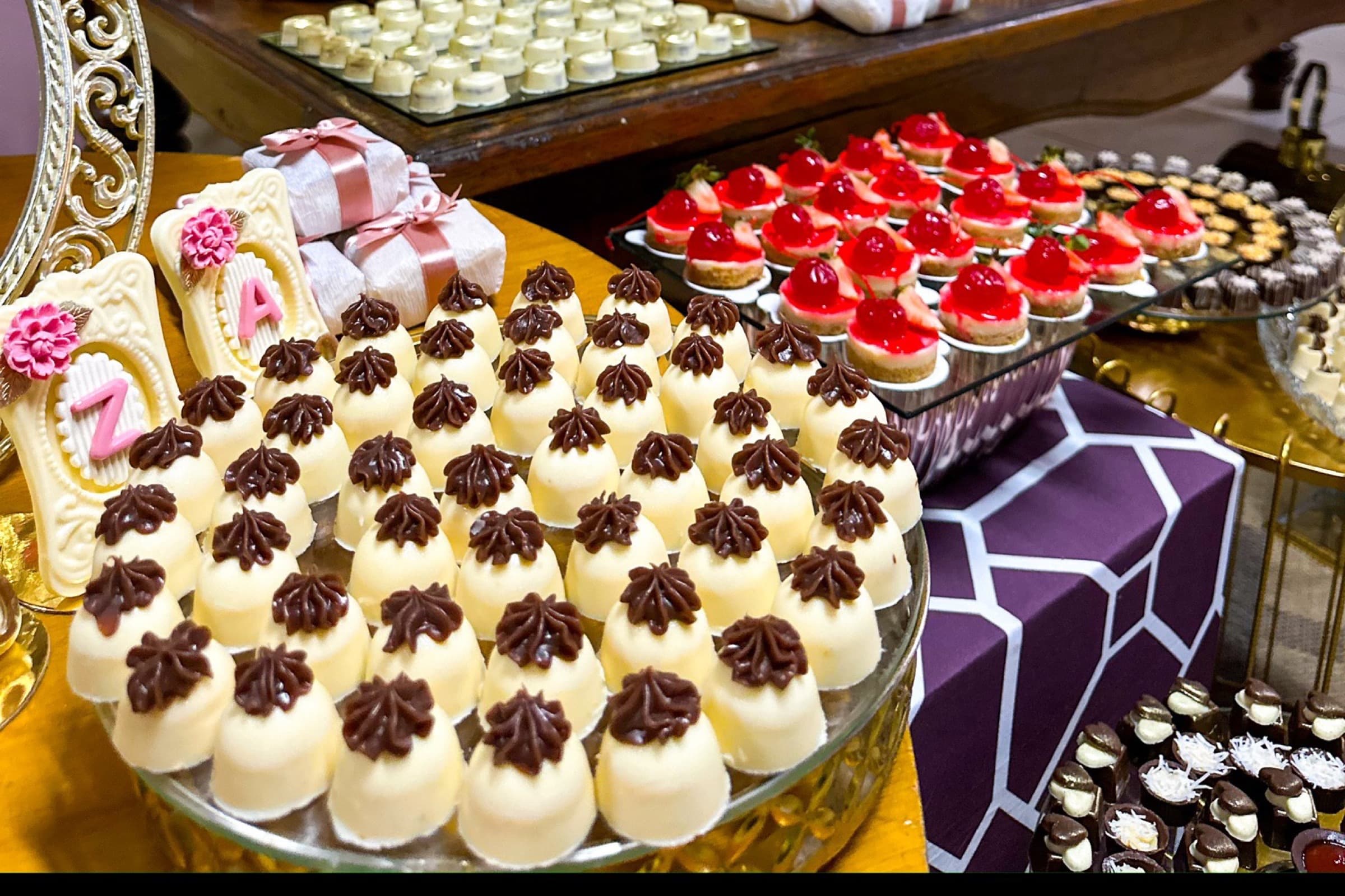 Chocolates nobres com flores douradas em bandeja espelhada